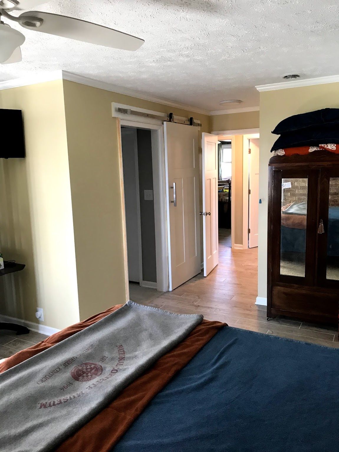 Bedroom interior with bed, sliding door, and closet. Pale walls, wood floors.