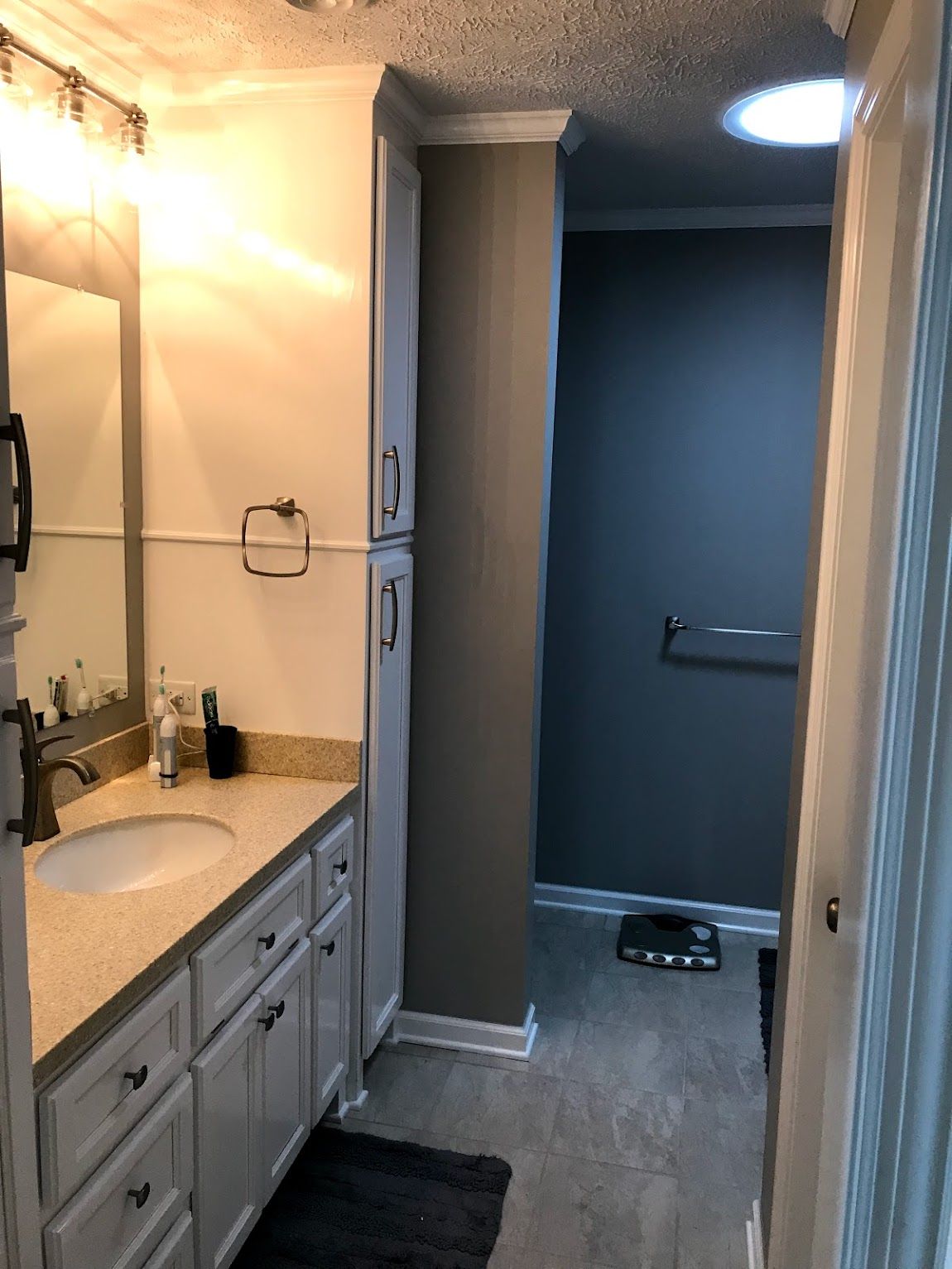 Bathroom with white vanity, gray walls, and a shower area.