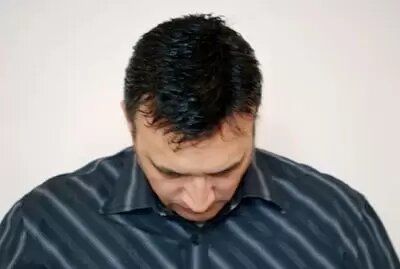 A man in a striped shirt is looking down.
