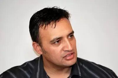 A man in a black striped shirt is looking at the camera.