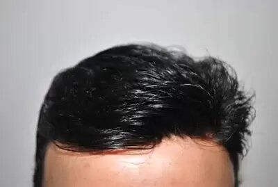 A close up of a man 's head with black hair against a white background.