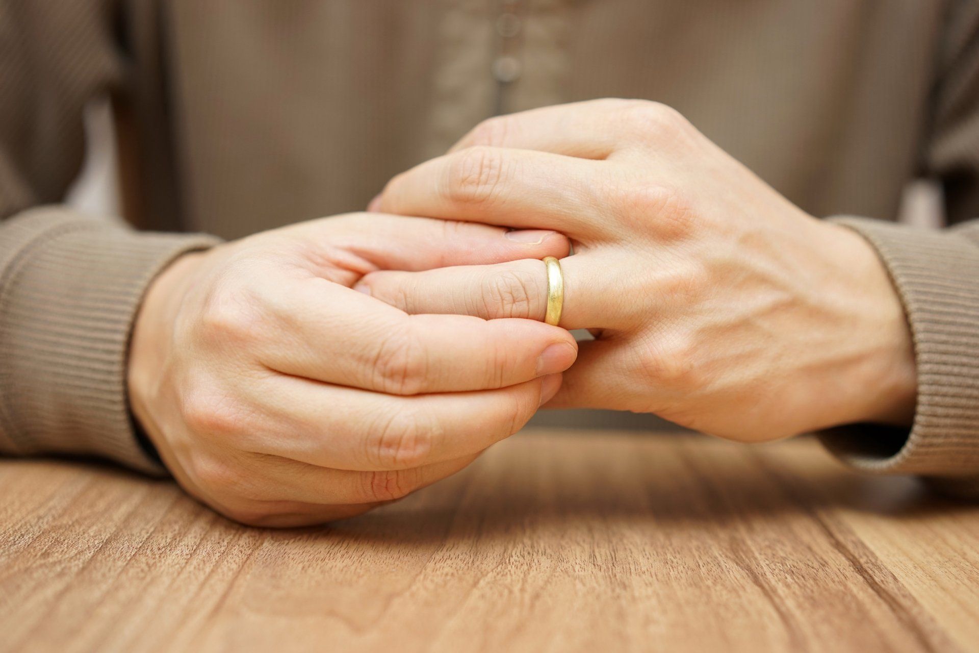 Woman's hands on a table, pulling off wedding band
