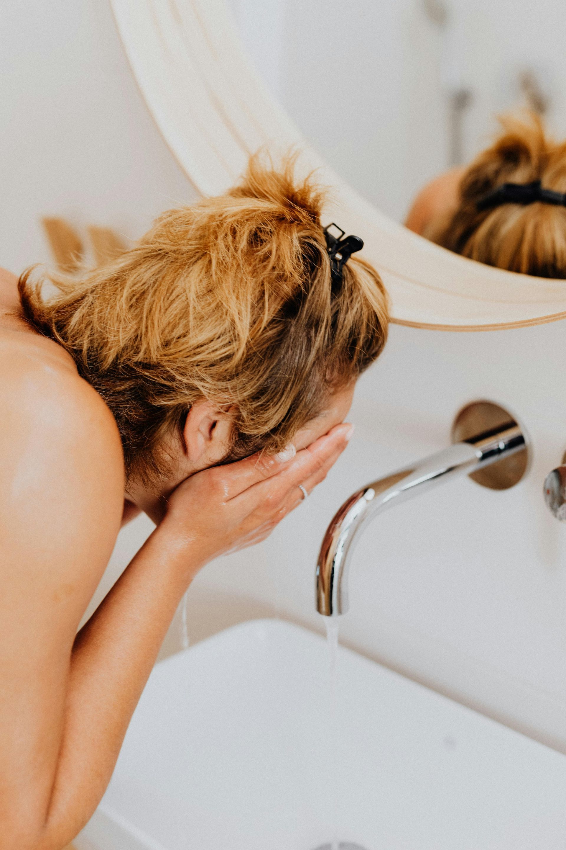 Two women are sitting on the floor in a bathroom next to a bathtub.