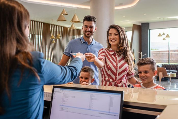 A hotel receptionist checks in a family at a modern front desk.