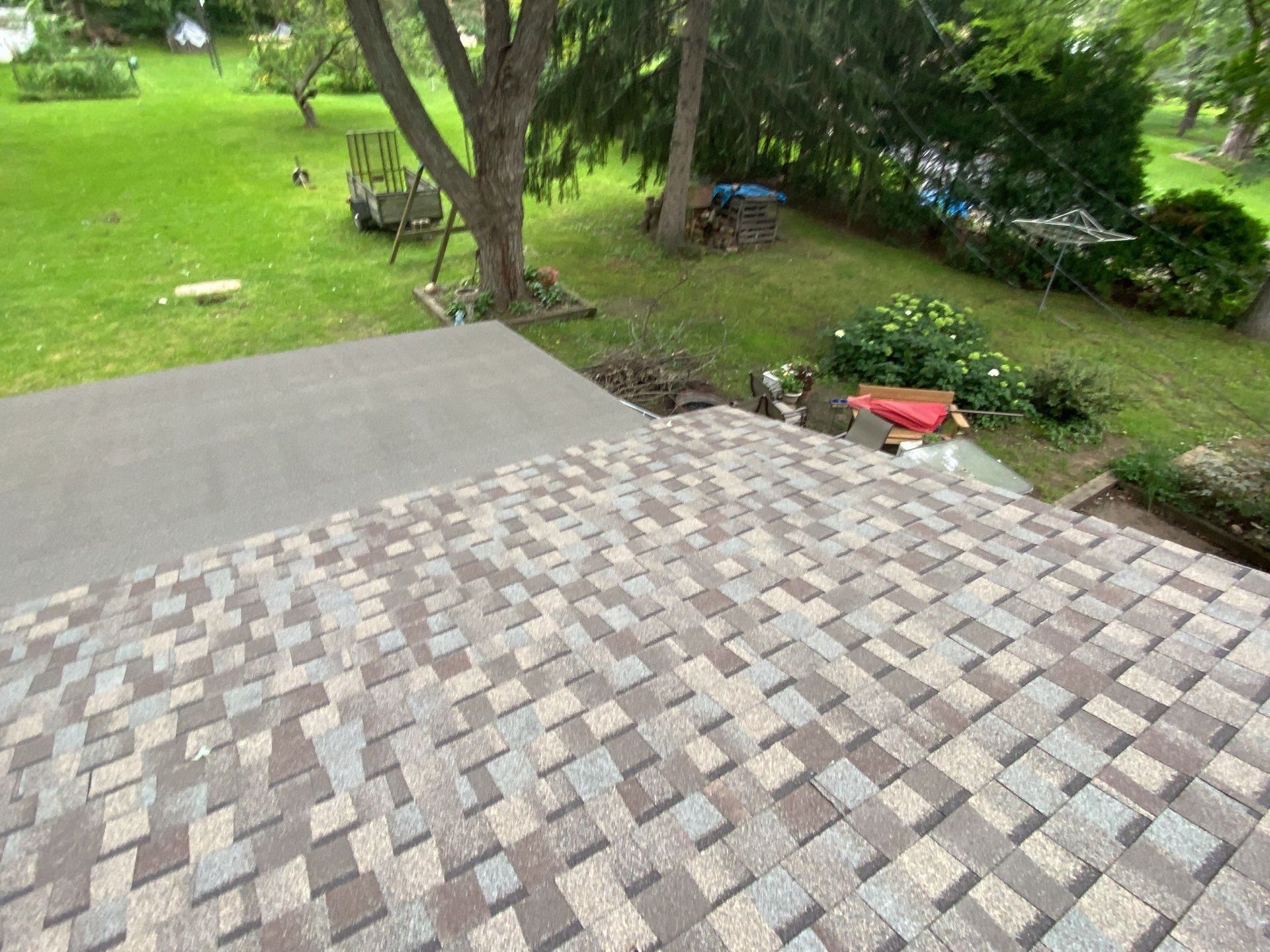 Stone patio leading to a green yard with trees and garden tools nearby