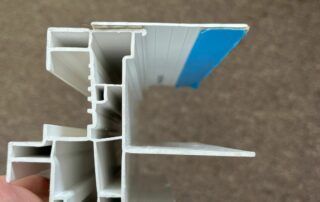 Cross-section of a white plastic window or trim profile with a blue protective film