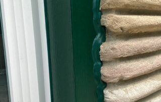 Close-up of stacked beige folded towels beside a green cabinet and white window frame