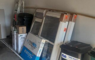 Stacked windows and miscellaneous items stored in a garage or utility room.