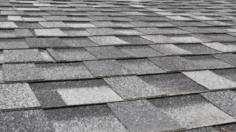 Gray asphalt roof shingles in overlapping rows, viewed from above.