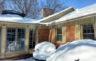 Snow-covered brick house with large windows and a sunlit roof