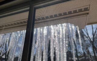 Icicles hanging from a roof eave, seen through a window on a sunny winter day