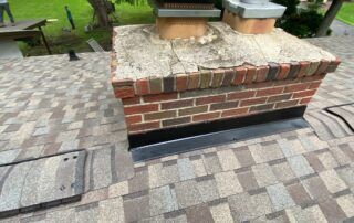 Brick outdoor structure with stone top and metal vents on a paved walkway