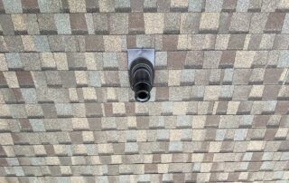 Small black security camera mounted on a patterned tiled ceiling.