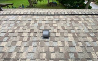 Small gray object on a tiled rooftop with grass and a street visible in the background
