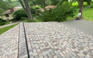 Stone retaining wall with a walkway beside a leafy yard; a person sits in the distance.