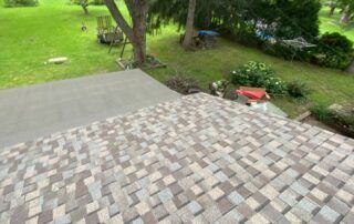 Stone-tile patio overlooking a green yard with trees and a red wheelbarrow