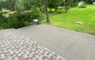 Stone patio beside green lawn and trees, with a person crouching near the edge.