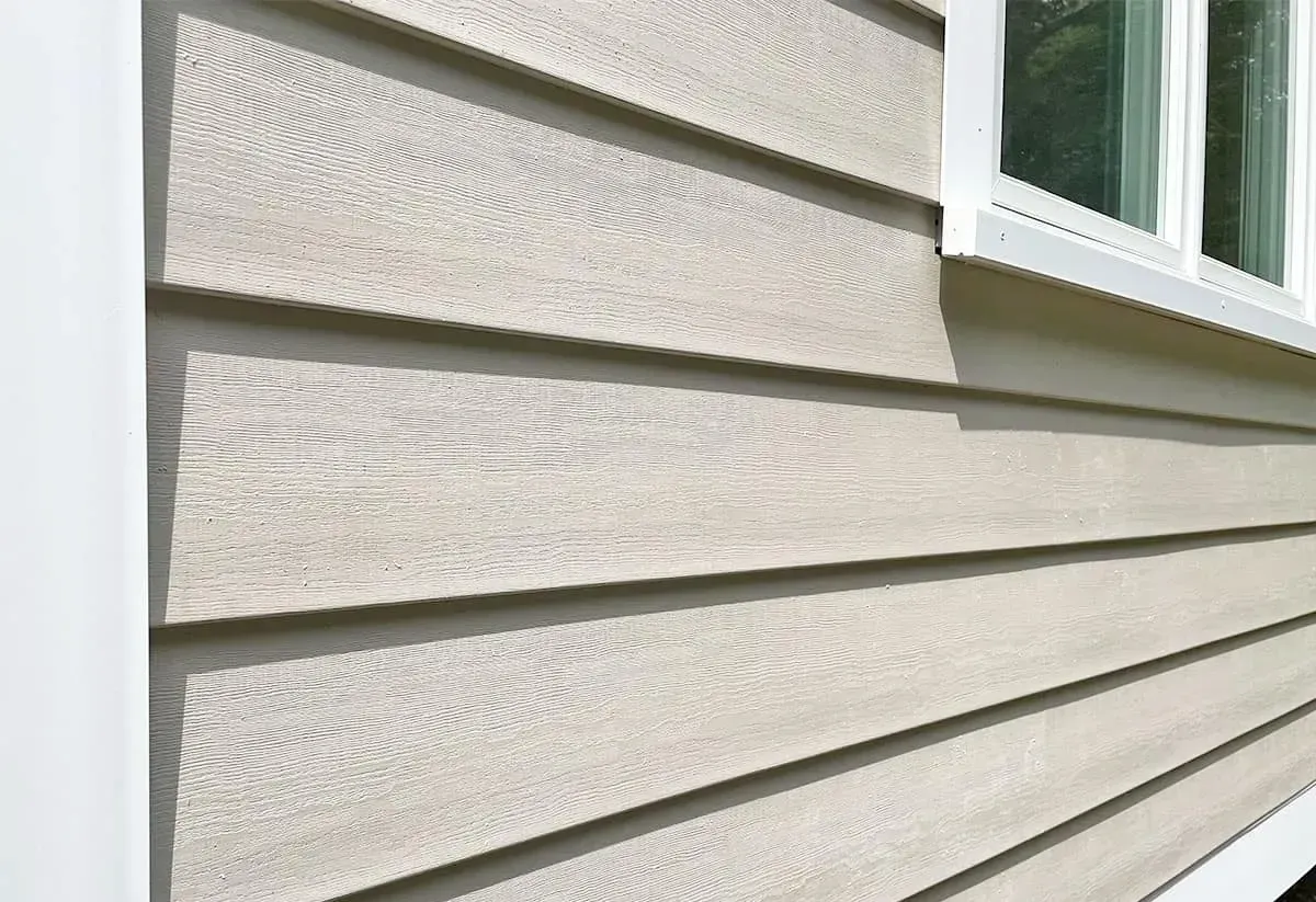 Close-up of beige house siding with a white-trimmed window