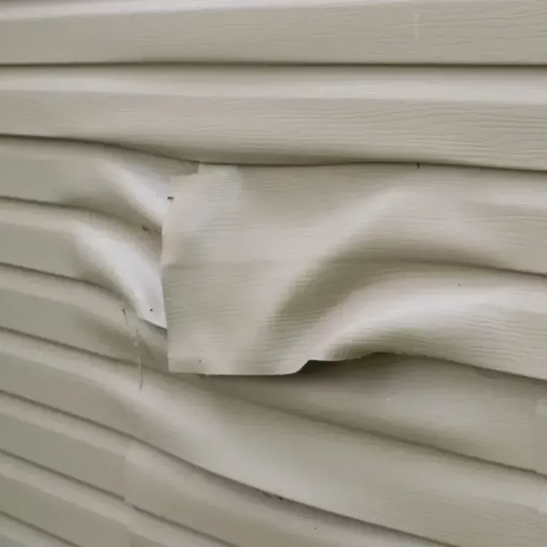 Crushed beige siding panel with a dented, wrinkled section and exposed nails