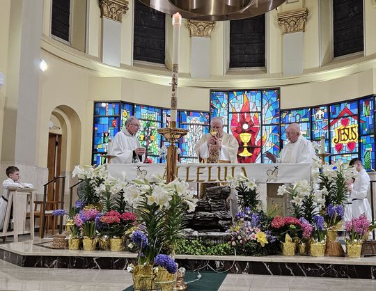 Three OMI members celebrate Mass behind an altar decorated with