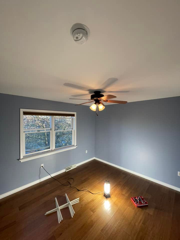 An empty room with a ceiling fan and a window.