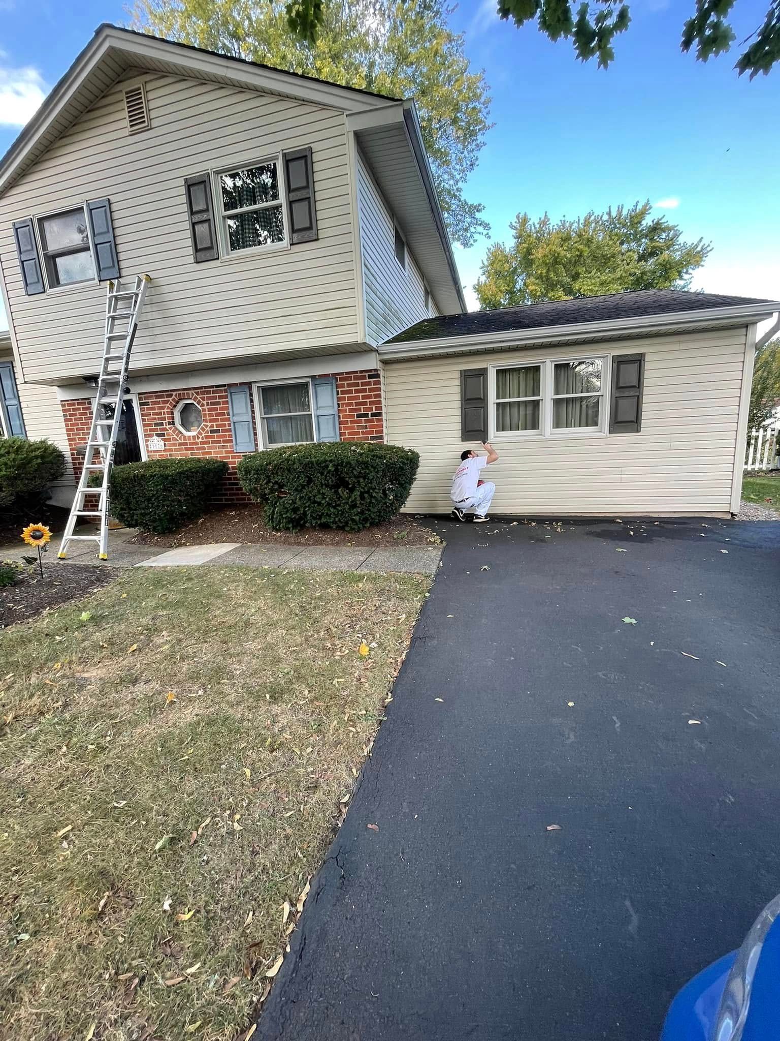 A man is standing in front of a house that is being painted.