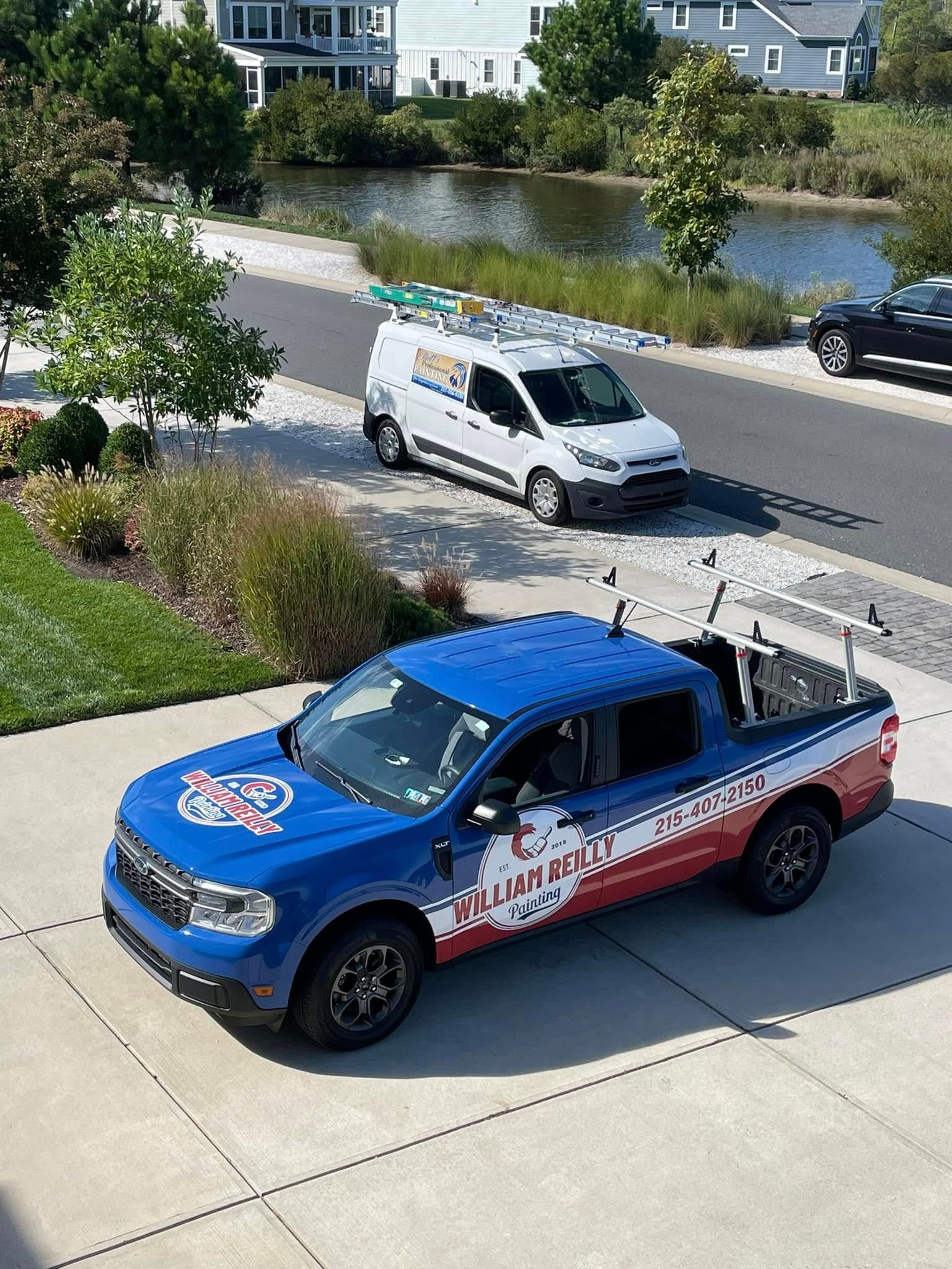 A blue truck is parked in a driveway next to a white van.