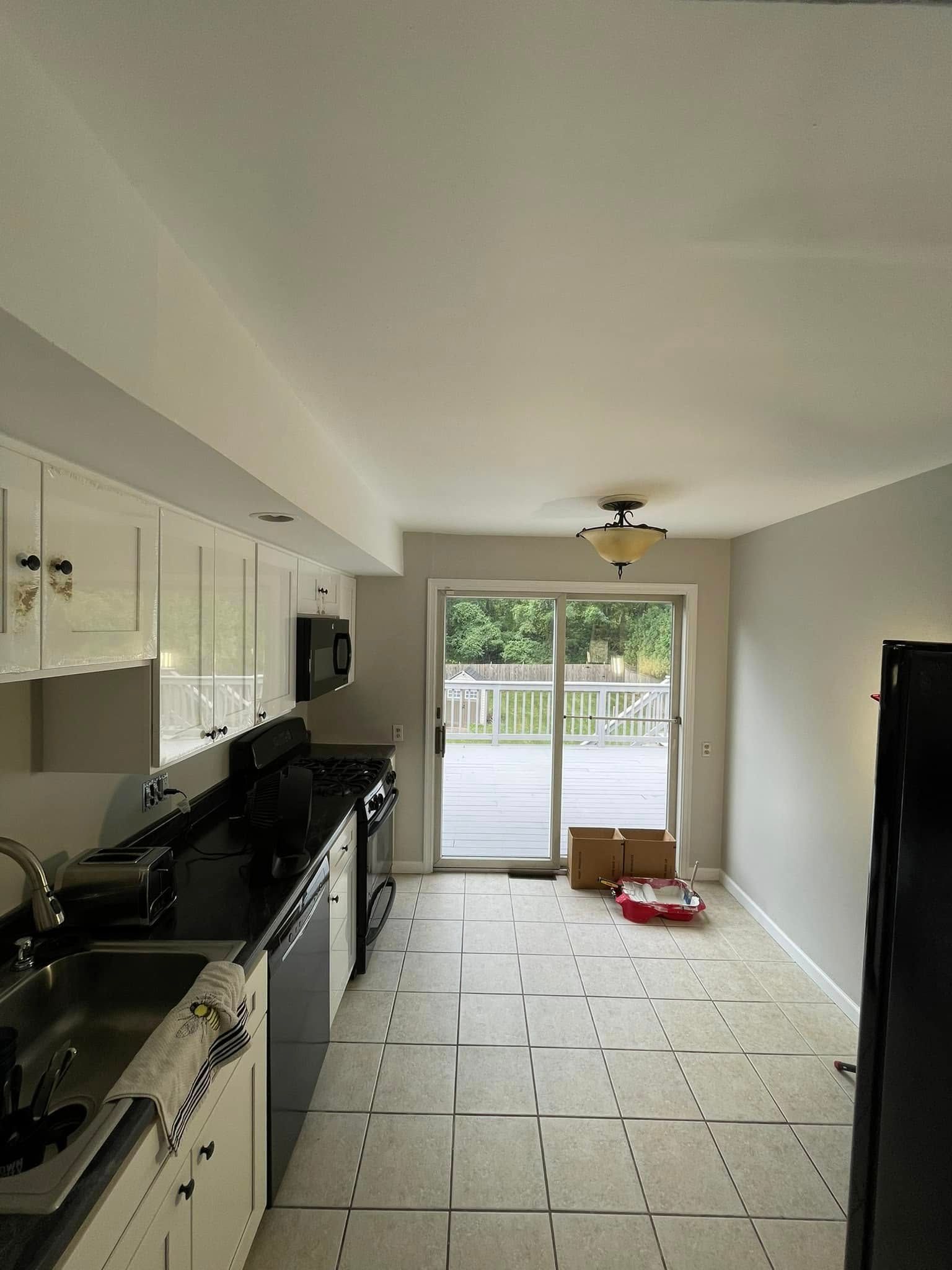 A kitchen with a sliding glass door and a black refrigerator.