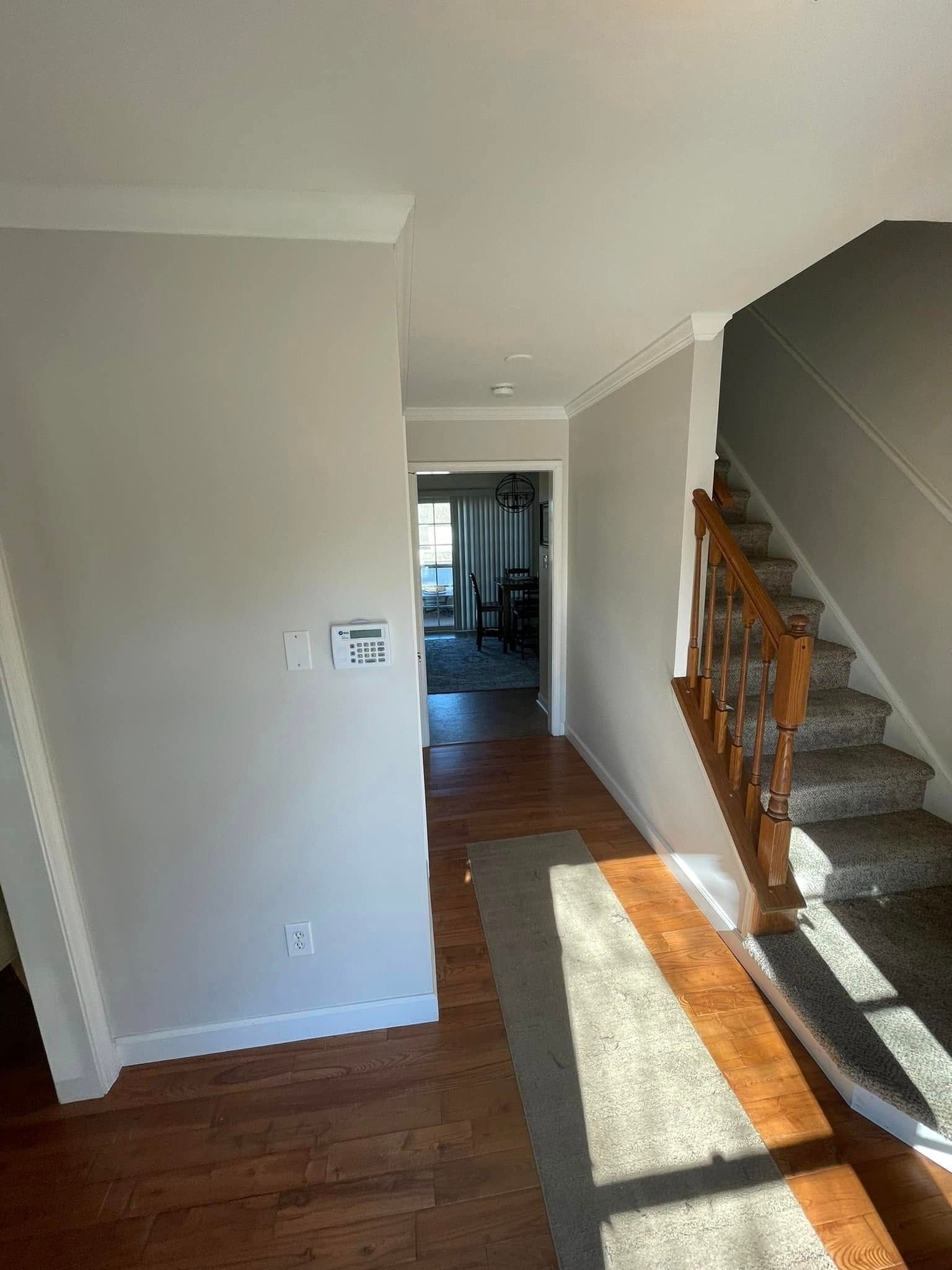 A hallway with hardwood floors and stairs in a house.