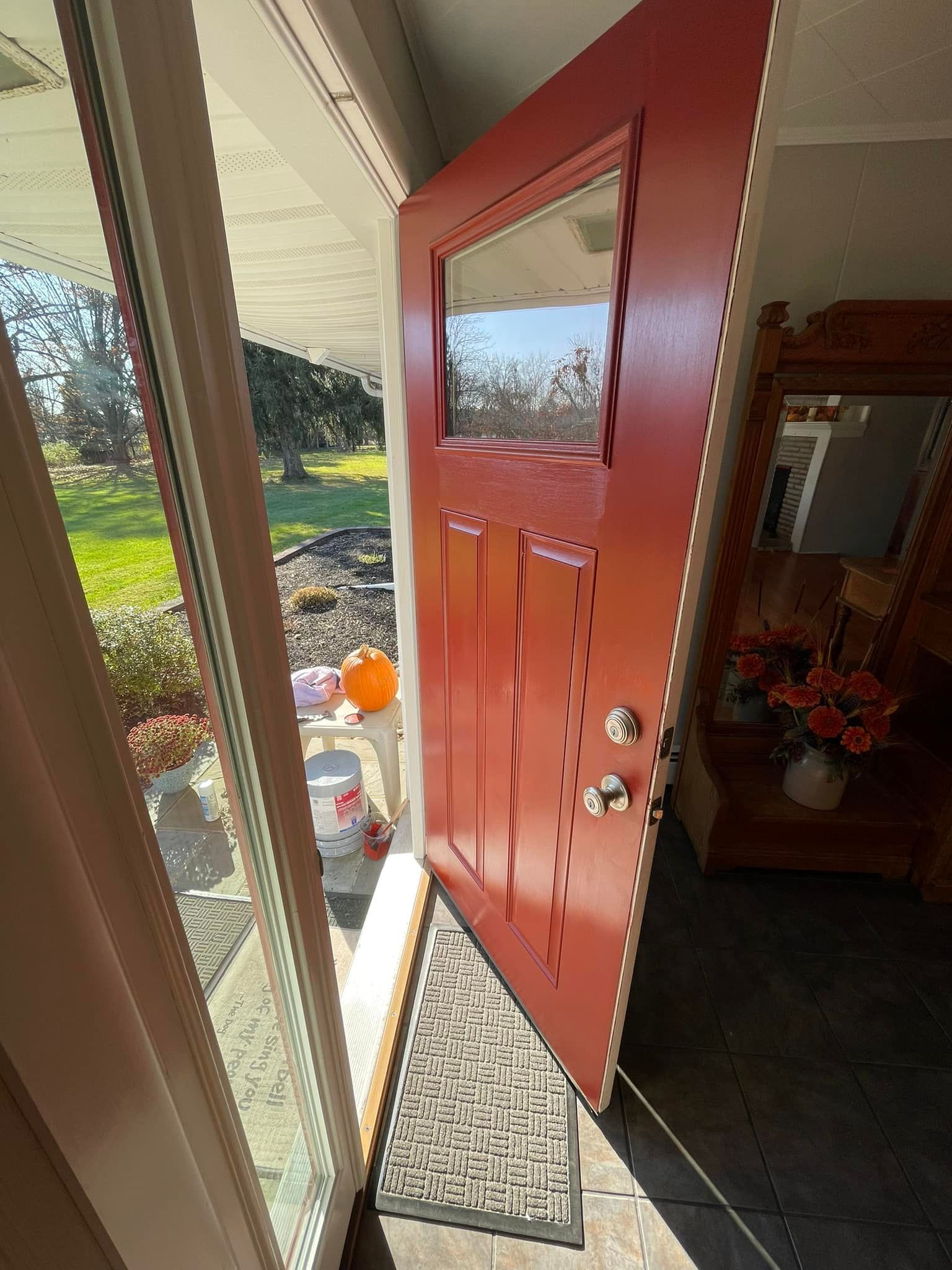 A red door is open to a porch in a house.