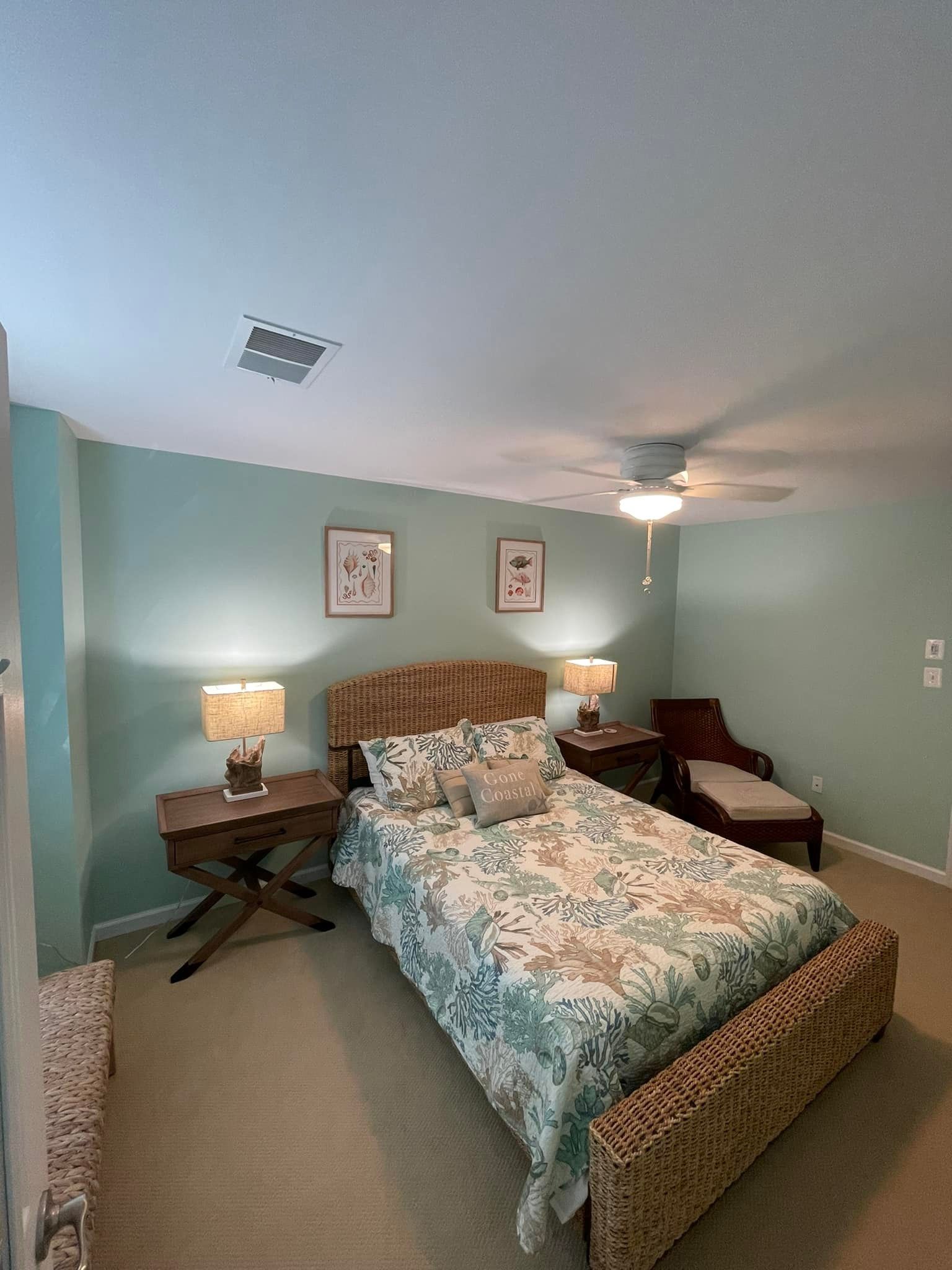 A bedroom with a bed , two nightstands , a chair and a ceiling fan.