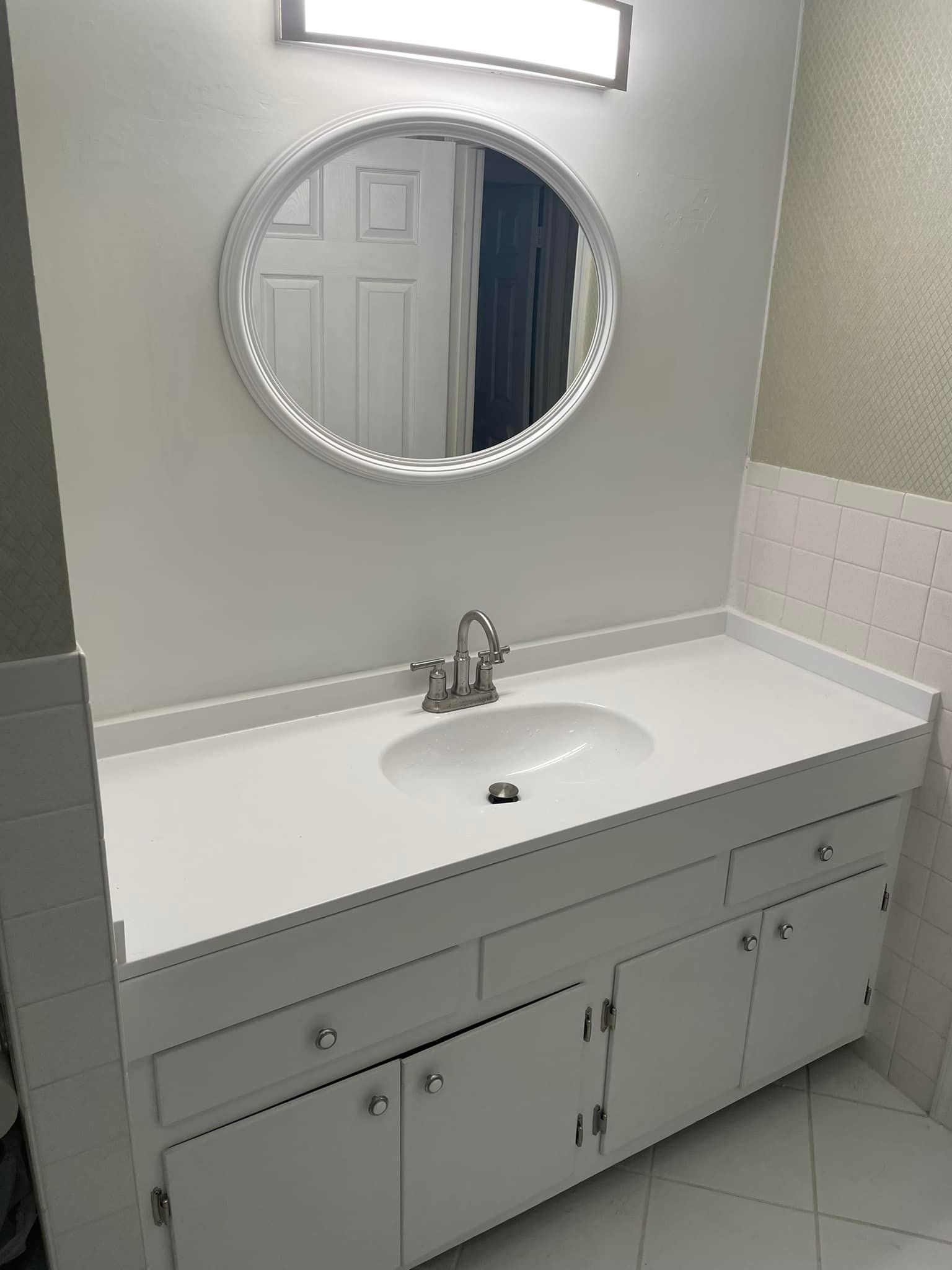 A bathroom sink with a round mirror above it.