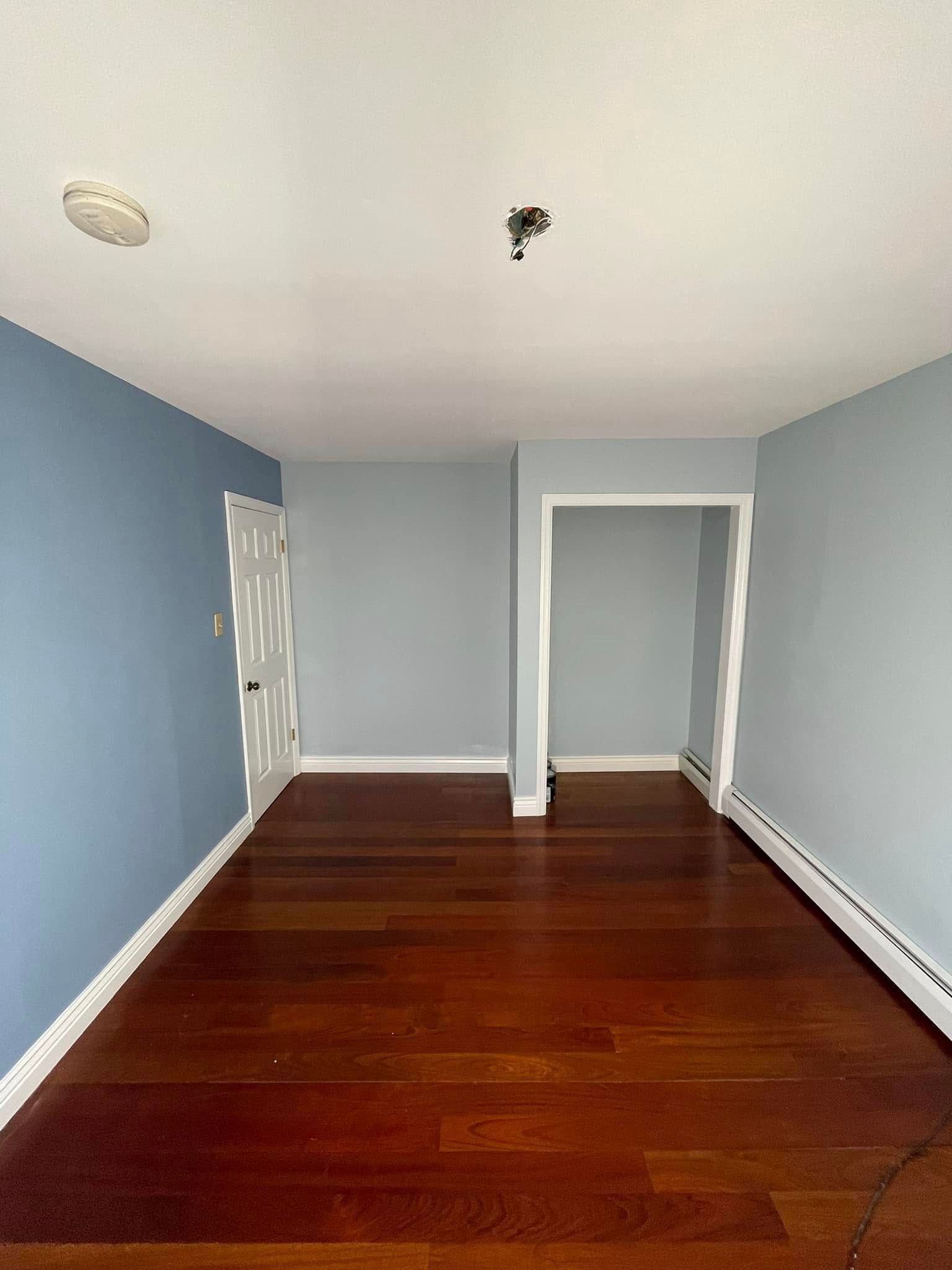 An empty living room with hardwood floors and blue walls.