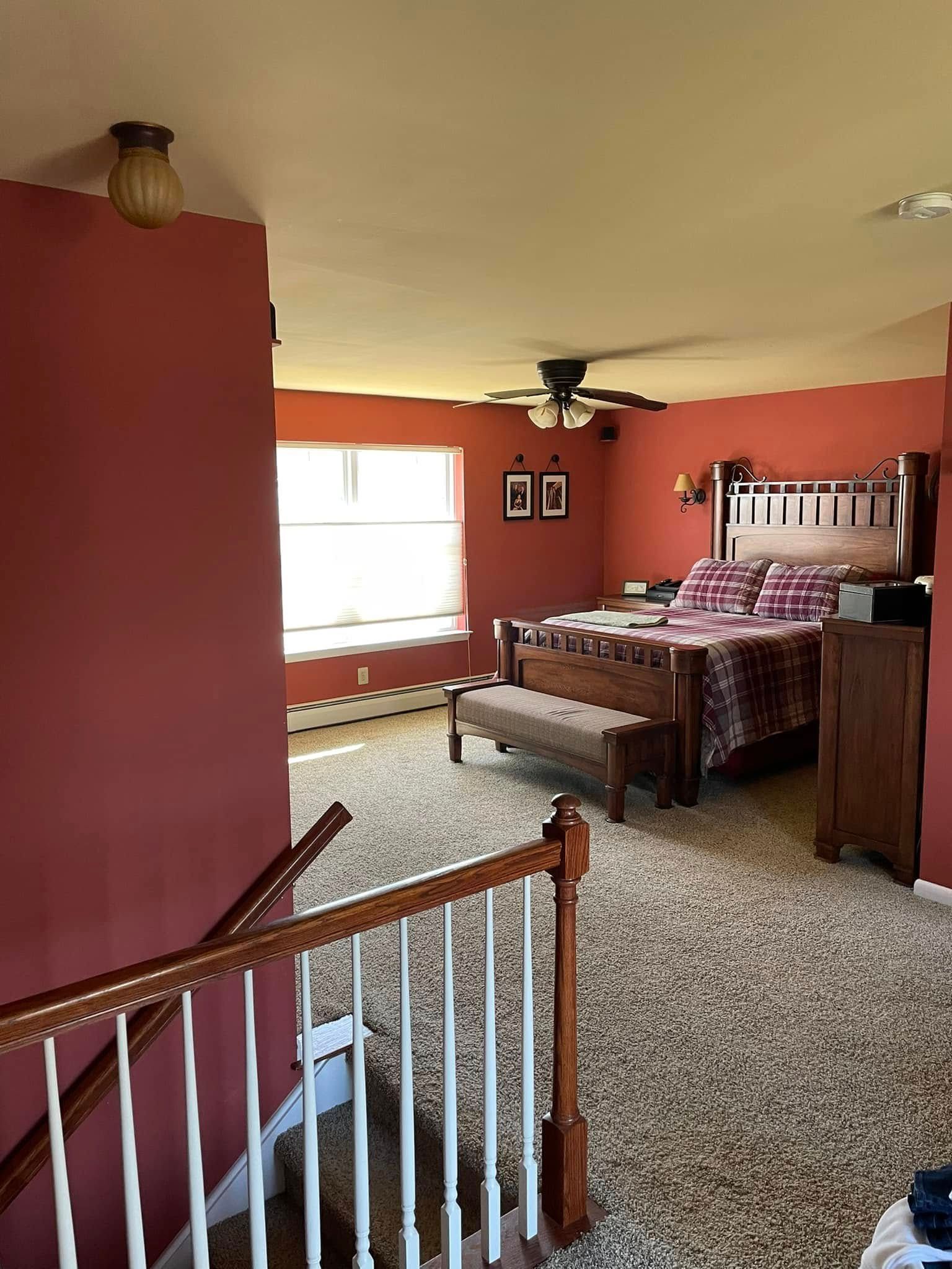 A bedroom with a bed , stairs and a ceiling fan.