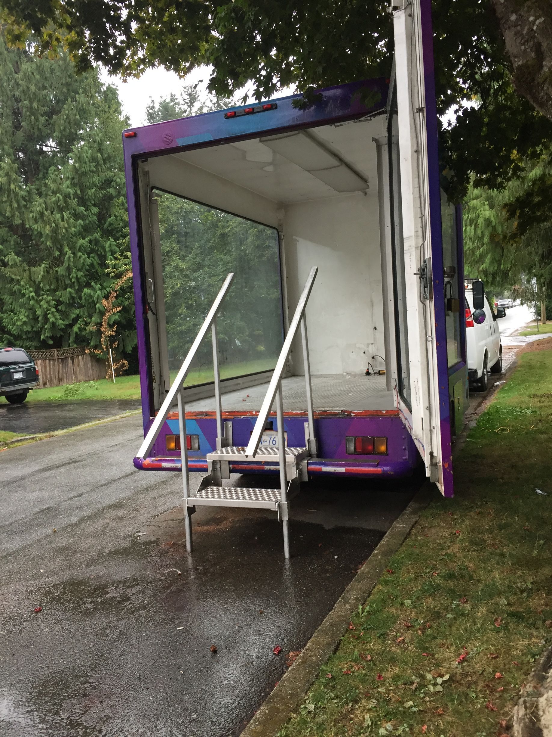A purple and white truck is parked on the side of the road.