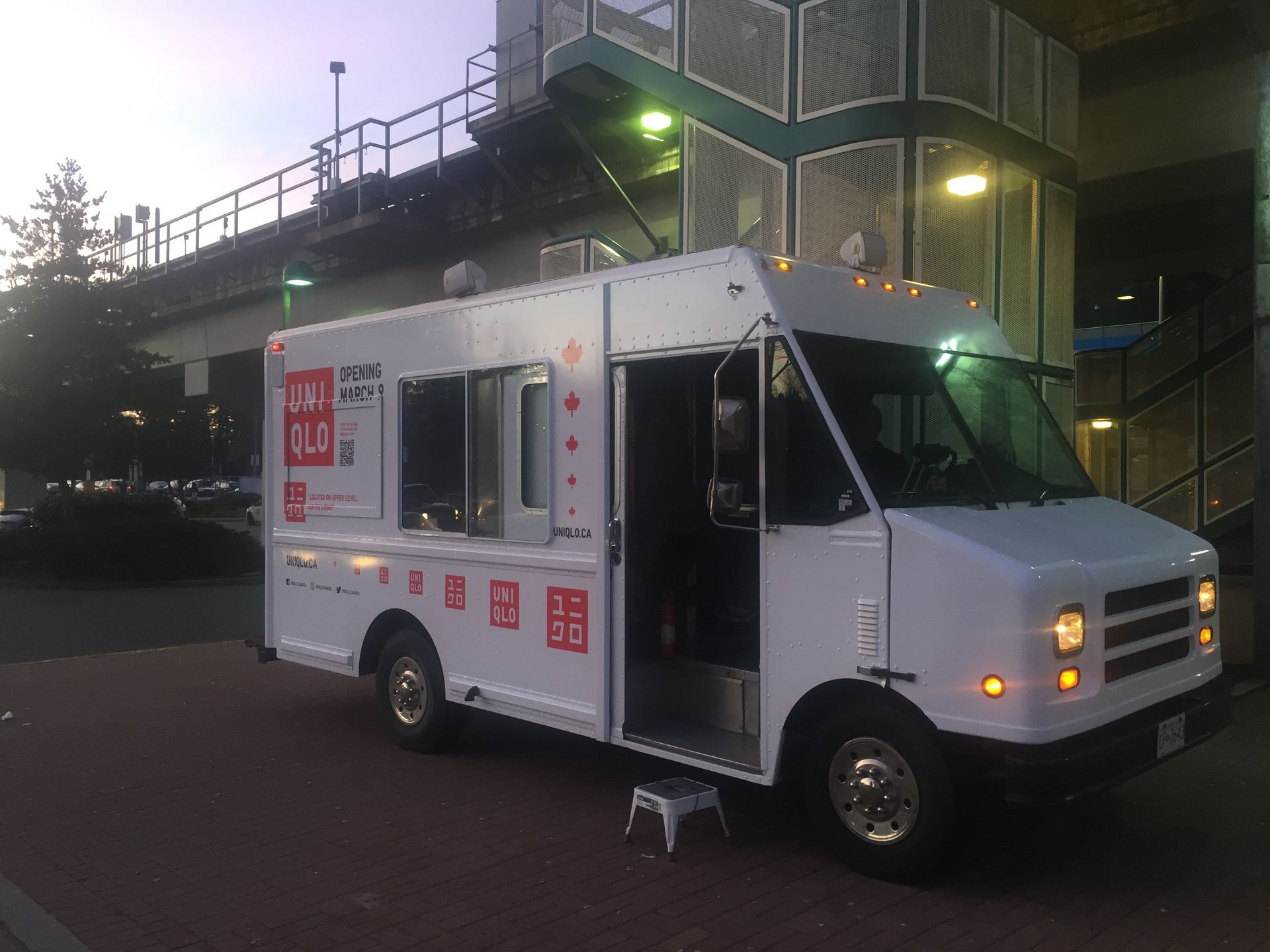 A white food truck is parked in front of a building