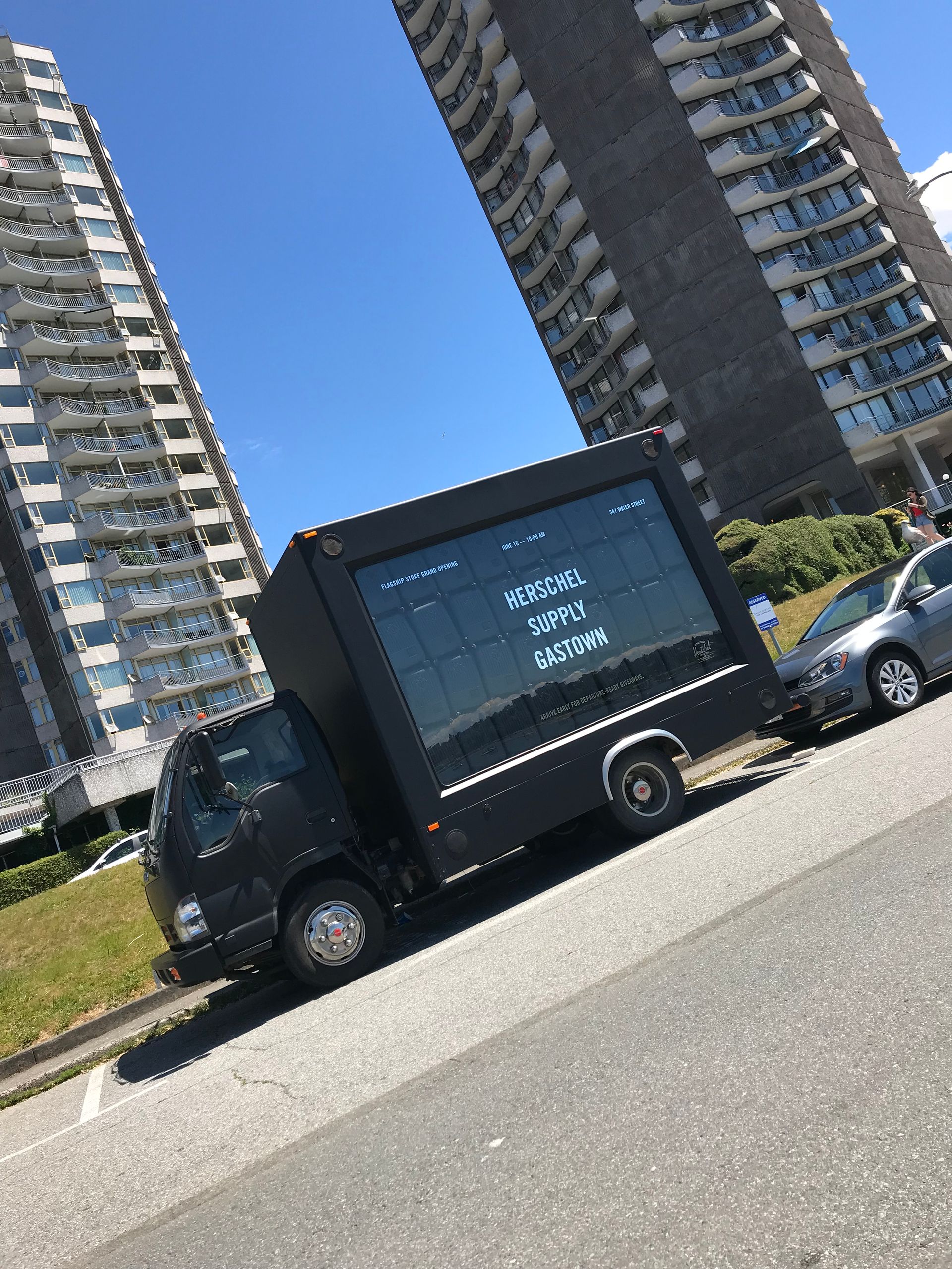 A truck is parked on the side of the road in front of a tall building.