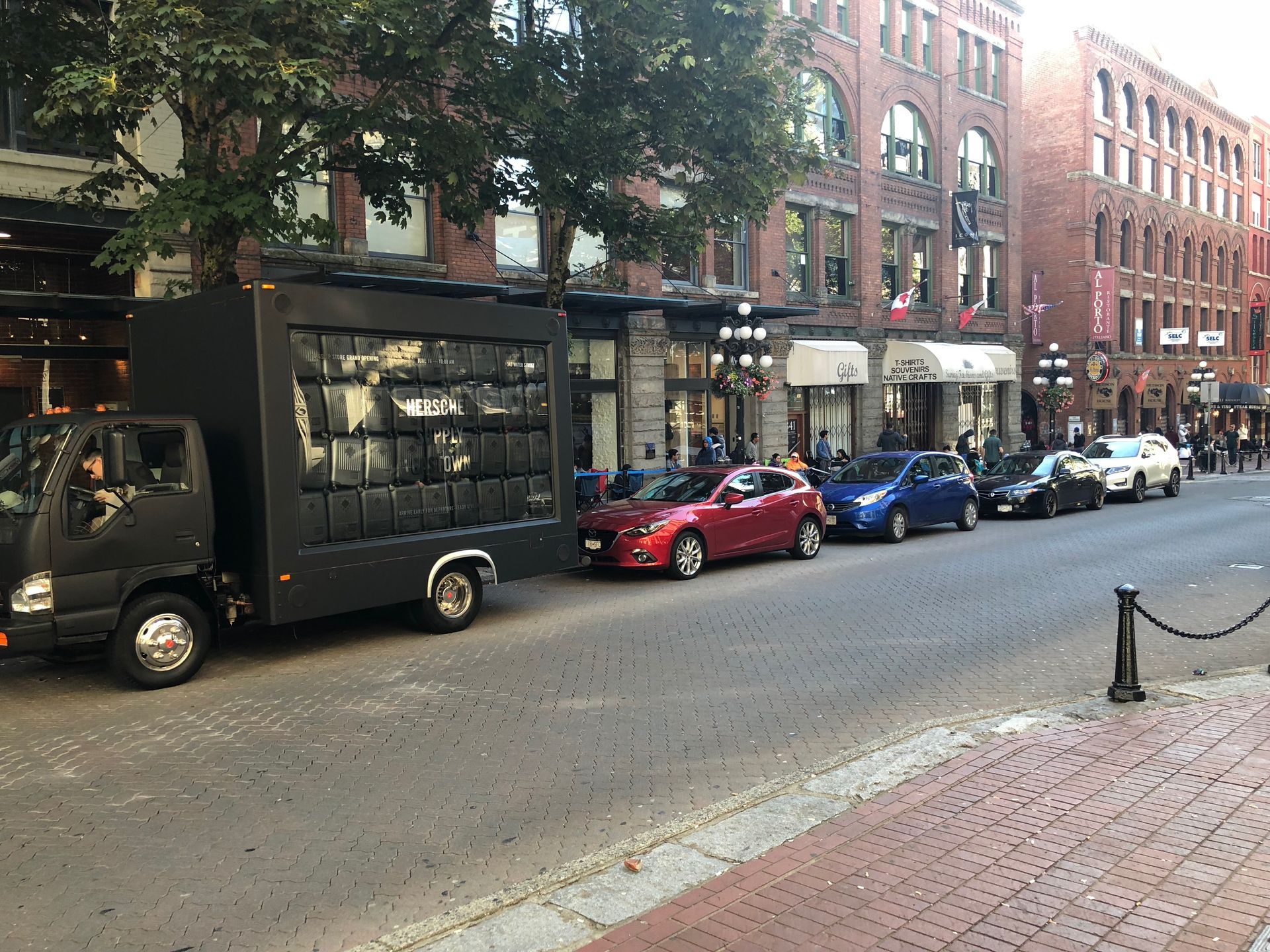 A row of cars are parked on the side of a city street.