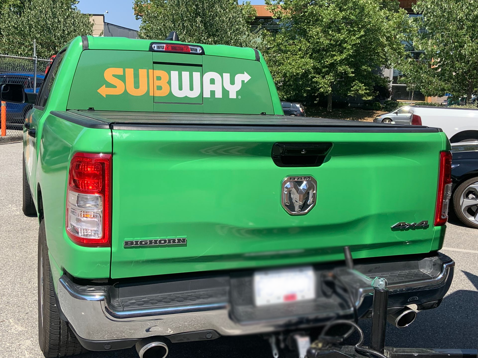 A green subway truck is parked in a parking lot.