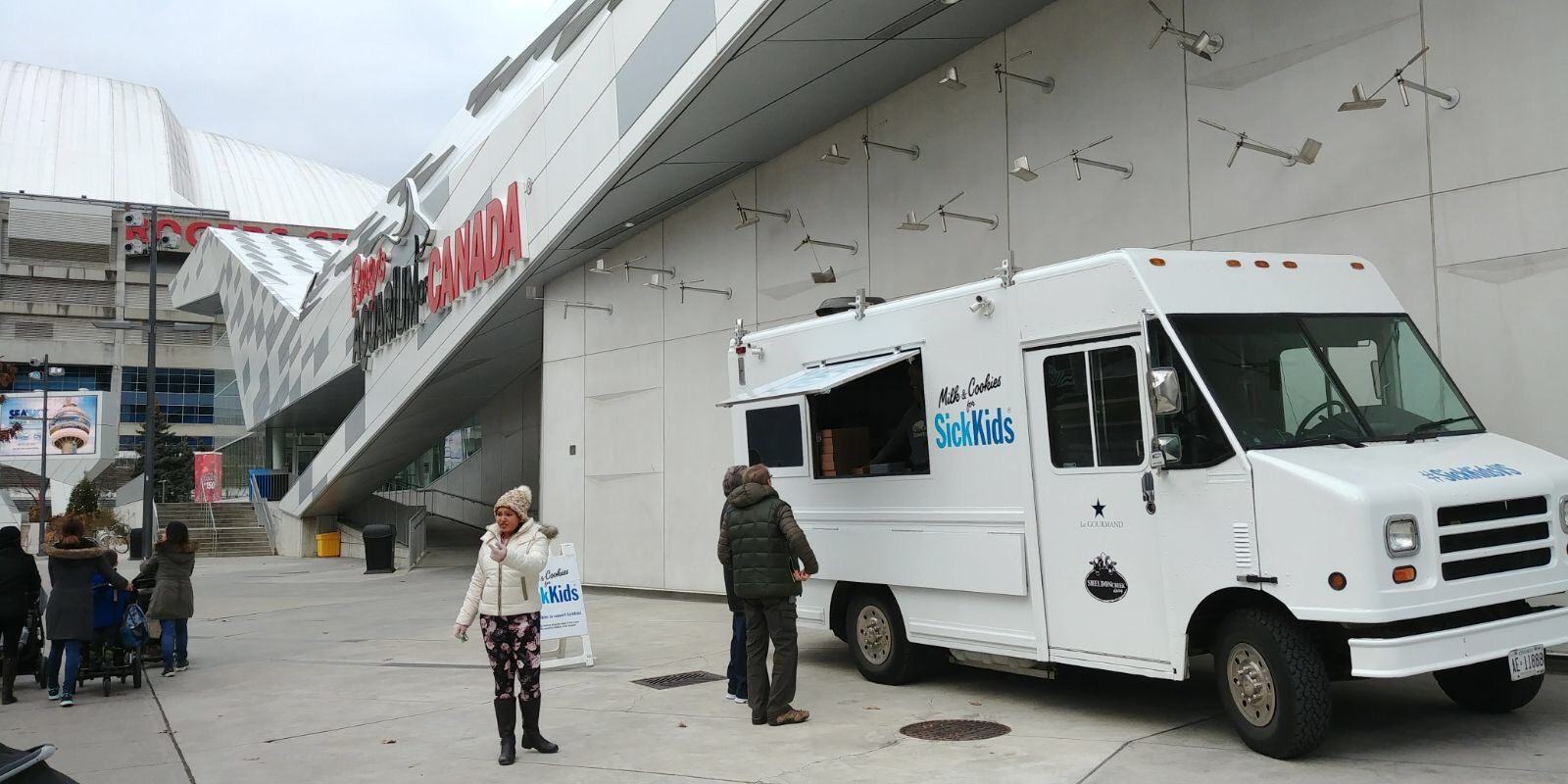 A white food truck is parked in front of a building