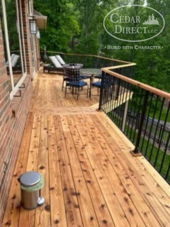 A wooden deck with chairs and a trash can on it