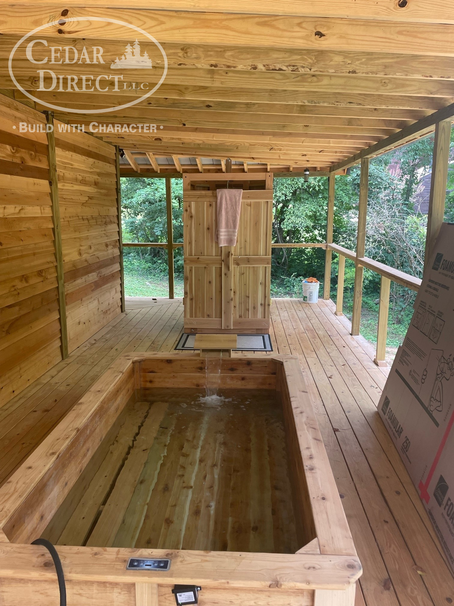 A wooden bathtub is sitting on top of a wooden deck.