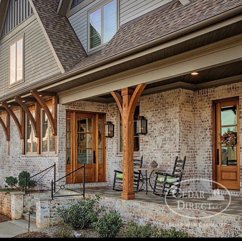 A brick house with a porch with rocking chairs and a table