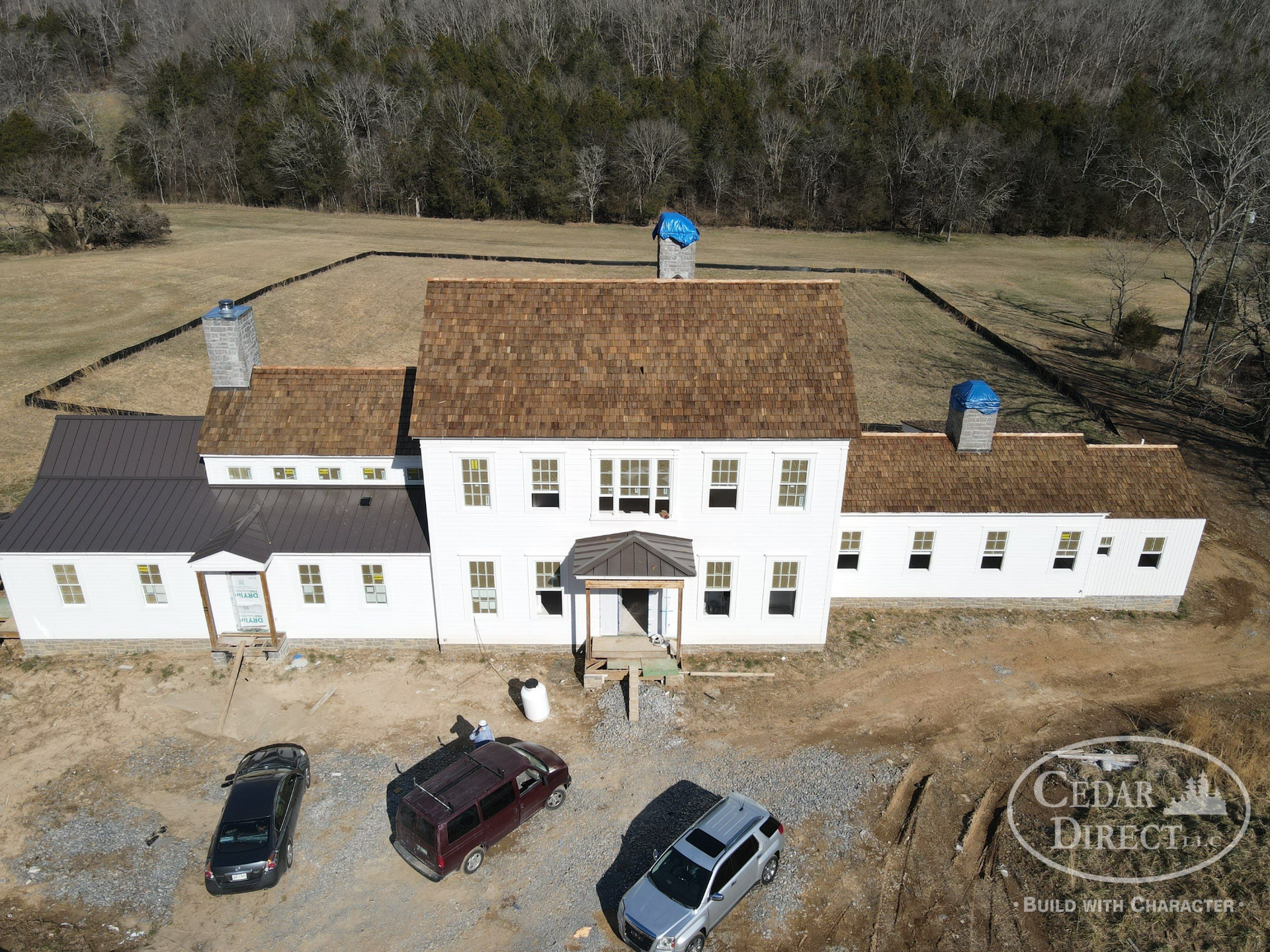 An aerial view of a large white house with cars parked in front of it.
