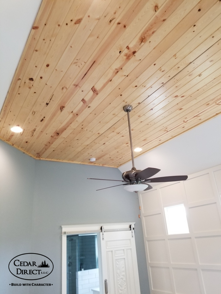 A bedroom with a wooden ceiling and a ceiling fan