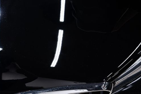 Black car hood reflecting white lights.