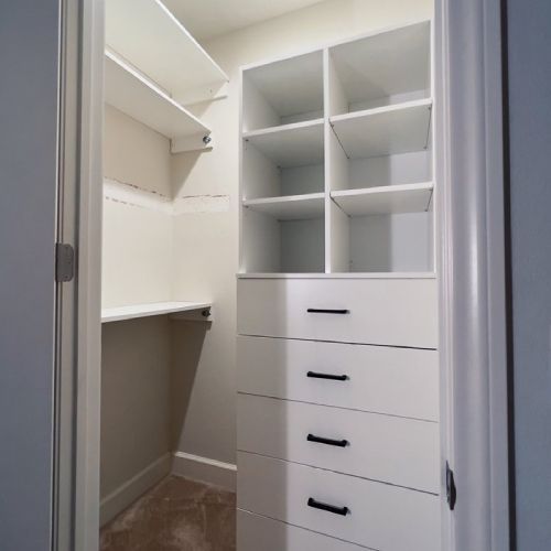A walk in closet with lots of shelves and drawers.