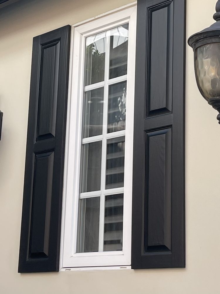 A window with black and white shutters on a house.