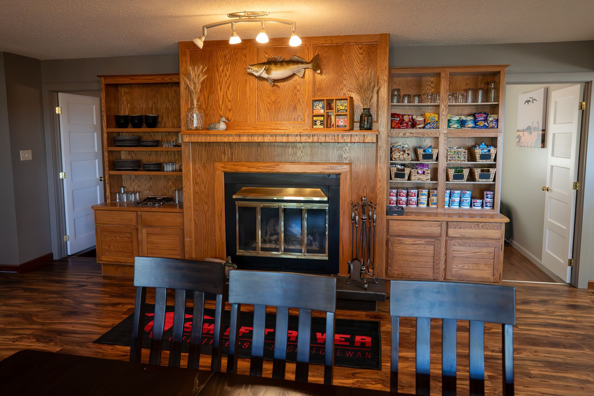 Living room with a wood-paneled fireplace, built-in shelves, and a dark wood dining table in front