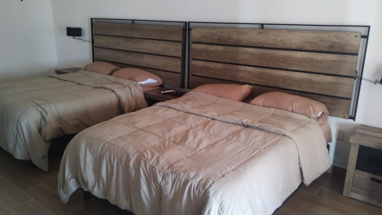 Two neatly made beds with beige bedding in a simple hotel-style room